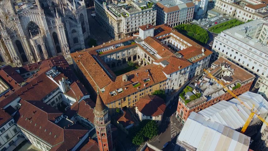 Aerial view of Piazza Duomo in front of the Gothic Catholic Cathedral in the center. Drone view of the gallery and rooftops during the day. Flight over the city. People live. Fashion city. Europe Mila