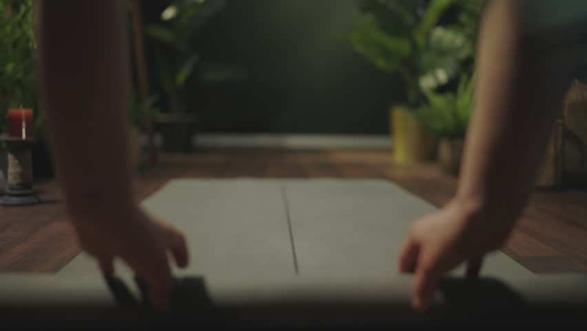 Closeup on middle aged woman with yoga mat folding mat in the green house.