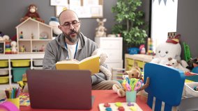 Young bald man preschool teacher reading story book on a video call at kindergarten