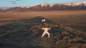 Video of kungfu master in a white sports uniform training on the hill. Man perform wushu forms in nature on background of snowy mountains at sunset time.
