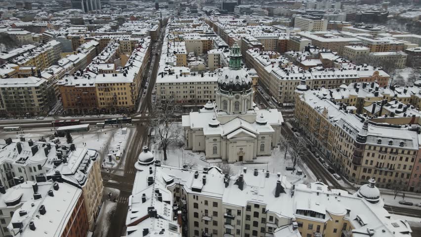 Aerial video of Stockholm, Sweden, Gustaf Vasa Odenplan church, in the background you see the whole city covered in snow