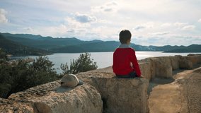 Boy sitting in ancient theatre and looking at the sea. 4k footage UHD 3840x2160 