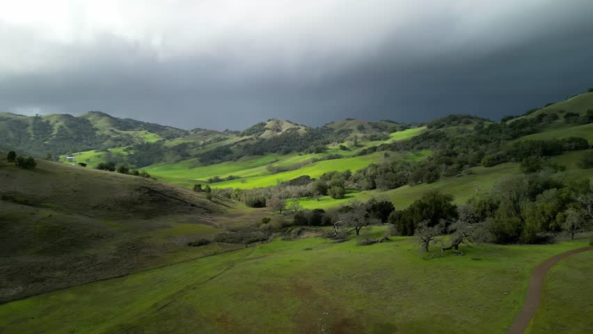 Beautiful light on green hilly landscape under dark storm clouds