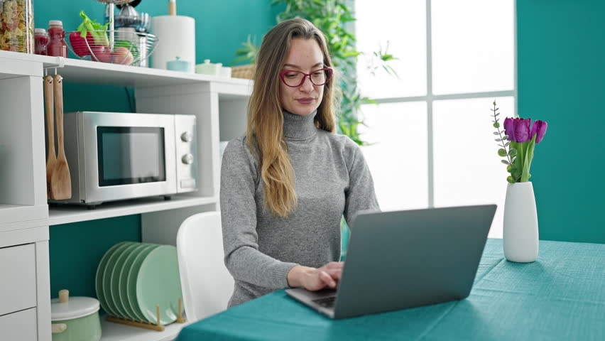Young caucasian woman using laptop stressed sitting on table at dinning room
