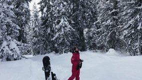 Woman snowboarder freerider standing in winter forest fir trees covered with snow drone video. Insanely beautiful mountain landscape
