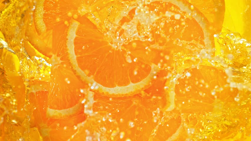 Super Slow Motion Shot of Fresh Orange Slices Falling into Lemonade Whirl at 1000 fps.
