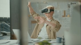 Young Concentrated Manager Architect Wearing Virtual Reality Headset during Work with New Project. Augmented Reality.Man Rolling Something Using Modern 3d VR Glasses Indoors in Bright Modern Office - Powered by Shutterstock - Get 15% off with code: PIKWIZARD15