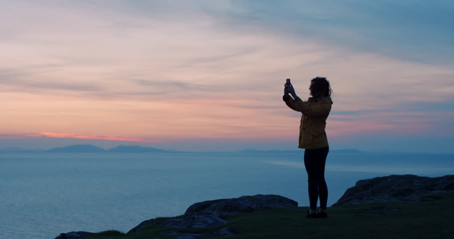 Sky, sunset and hiking with woman silhouette, landscape photography with smartphone, fitness and hike on cliff with sea view. Travel, adventure and ocean with freedom mockup, mountain and nature. | Shutterstock HD Video #1101724597