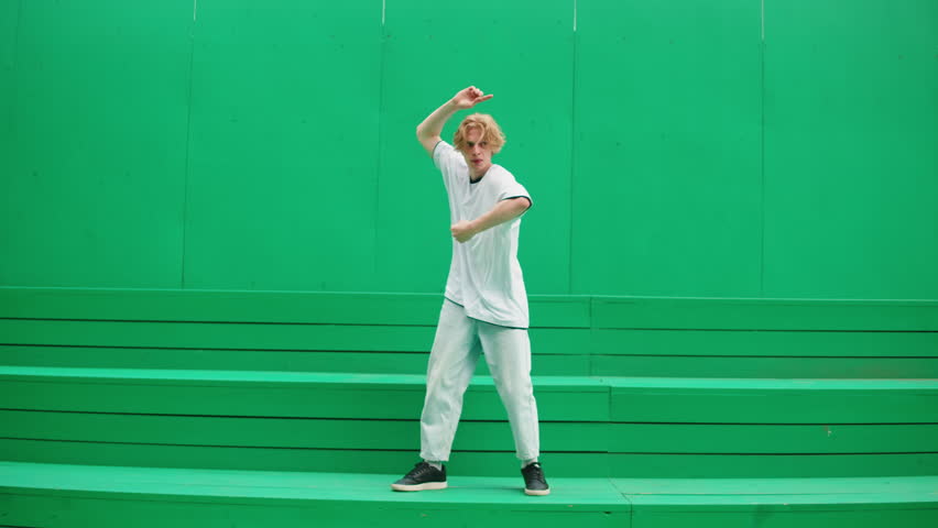 Young man dancing hip hop. Modern dance choreography. Professional breakdancer training on green background, dancer showing dance movings outdoor. Musical video.