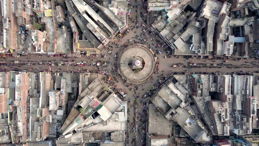 A top-angle rotating movement Aerial drone shot of a crowded or congested crossroads in a busy market with people, vehicles, bikes, and vendors passing on the street, in New Delhi, India Royalty-Free Stock Footage #1101730669
