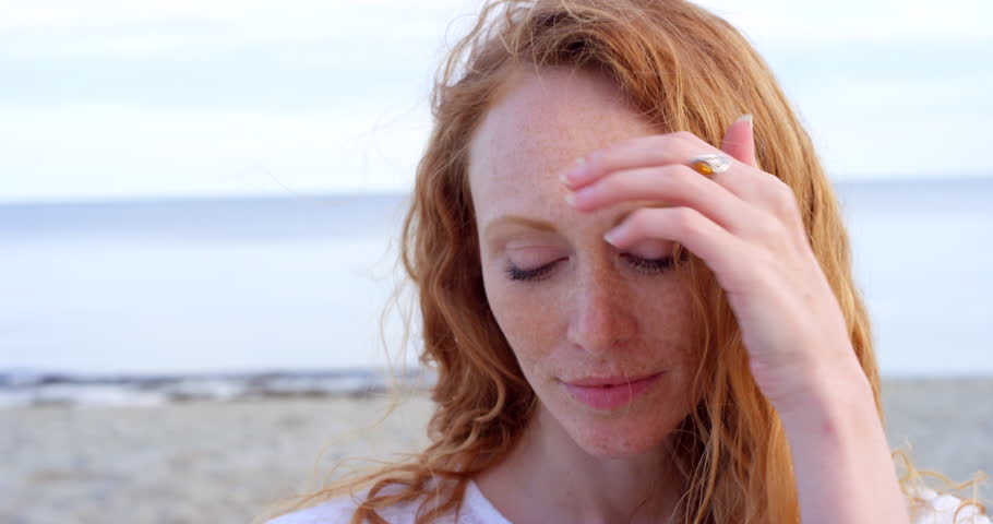 Portrait of woman, face and wind at beach for travel, beauty and relax on holiday, vacation and break at sea in Scotland. Young ginger female, fresh air and freedom by ocean, nature and peaceful day | Shutterstock HD Video #1101731051
