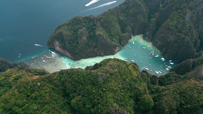 Aerial top view iconic tropical turquoise water Pileh Lagoon surrounded by limestone cliffs, Phi Phi islands Thailand. Scenic Pileh Lagoon or Pileh Bay filled with boats on tropical island in Thailand | Shutterstock HD Video #1101732353