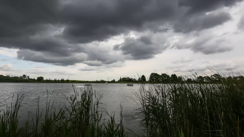 timelapse of storm cloud gliding in sky over calm lake, windswept ripples