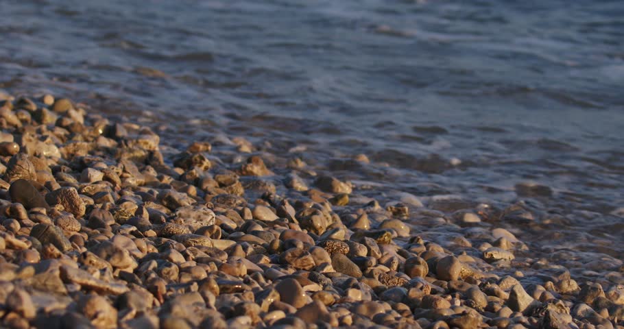 Waves on golden light of sunset on the pebble beach in Peljesac, the Adriatic Sea in Croatia | Shutterstock HD Video #1101739517
