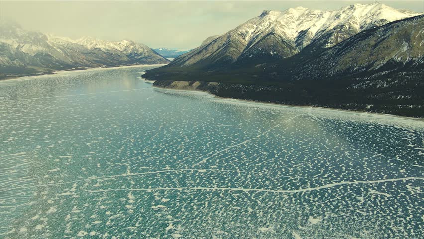 Panoramic aerial view to the Abraham Lake, Canada. Drone smoothly rises from the wild forest. Wild Canadian nature and landscape from above. Alberta aerial. 