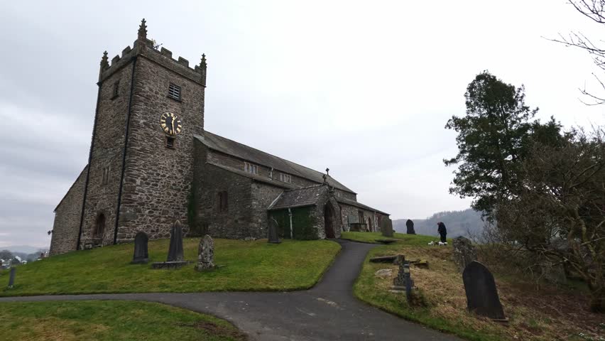 St Michael and All Angels Church in Hawkshead, showing fields and grazing sheep Cumbria, UK