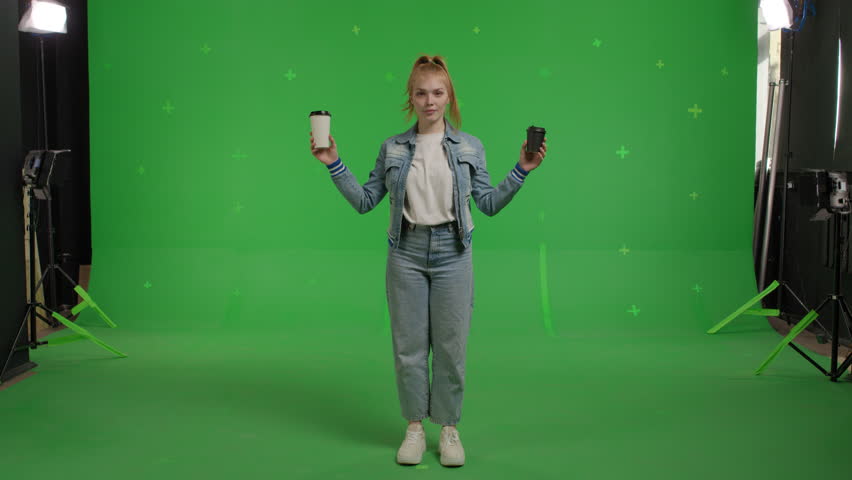 Young redhead caucasian woman drinking coffee cup refreshment with green screen backdrop, Girl makes a choice between two cups of beverage over chroma key background