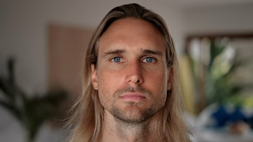 Unhappy male person face home portrait. Blue eyes look at camera close up. Sad bristle surfer man long hair. Upset shy guy. Kind people portraits. Young adult hippie inside house. Hipster hairstyle. Royalty-Free Stock Footage #1101745333
