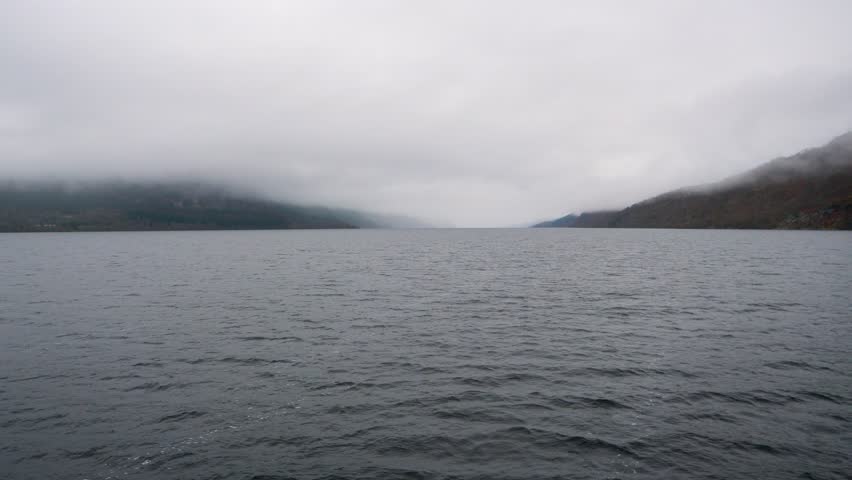 Loch Ness in the highlands of Scotland, filmed from the water, with low-lying clouds and mist on an overcast grey day