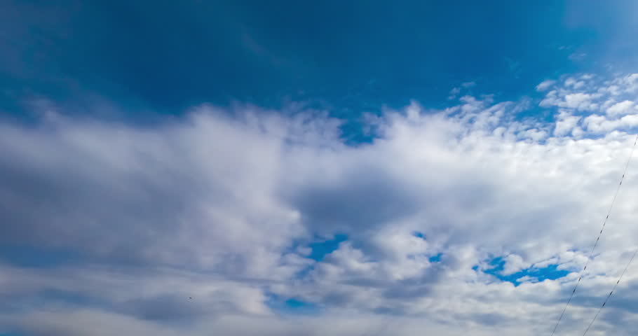 Soft light clouds quickly flowing by the horizon. Heavy grey clouds changing soft ones. Low angle view. Timelapse.