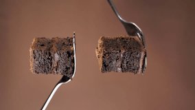 poured into two pieces of chocolate cake on forks on a brown background. vertical video