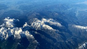 Airplane window. Wide angle. 360 degrees. The guy on the plane, the young man with glasses in a medical protective sterile mask on his face. View of the mountains and clouds. Milan, Italy, 03.2023 - Powered by Shutterstock - Get 15% off with code: PIKWIZARD15