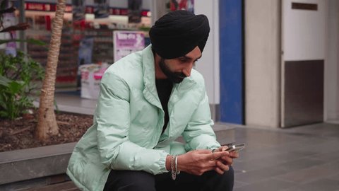 Indian Sikh Man With Black Turban Using Smartphone Outdoor. Close Up วิดีโอสต็อก