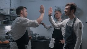 Chef stands with employees and talks before start of work. The cook in apron starts to cut sweet potato. Colleagues prepare dishes at background. Teamworking concept at restaurant kitchen. Slow motion - Powered by Shutterstock - Get 15% off with code: PIKWIZARD15