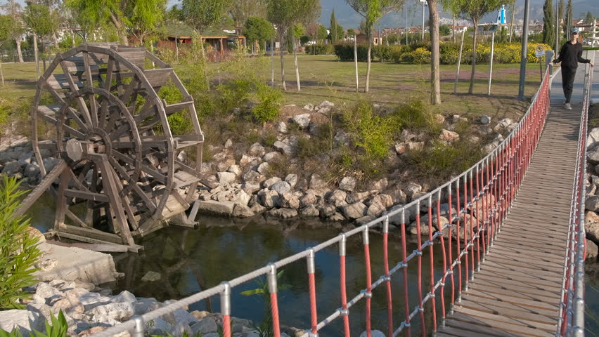 A happy teenager walks along a suspension bridge in the park.