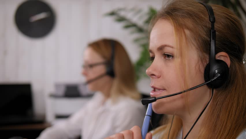 Telesales agent wear wireless headset microphone, consult customer support service on phone call center concept. Close-up. Blurred woman in the background.