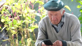An elderly grandfather is learning to use a smartphone. 