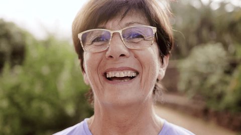 Стоковое видео: Portrait of happy senior woman looking at camera outdoor with park city on background - Elderly healthy lifestyle
