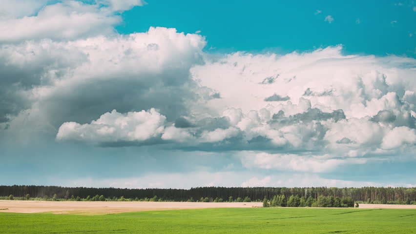 Colorful Cloudy Blue Sky Fluffy Clouds Above Grassland. Sky With Clouds On Horizon Above Rural Landscape Meadow. Background 4k Time Lapse. Dramatic Sky With Clouds Above Countryside Rural Field