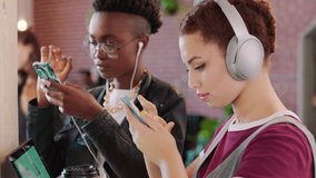 Technology, smartphone and creative people in office workspace and internet inspiration, social network or video audio streaming on mobile app. Gen z student women with headphones scroll social media