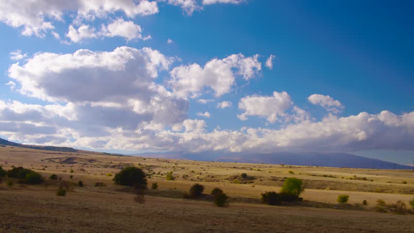 Time lapse clouds in landscape and mounteins with blue sky, sunny rays shining, summer sunny beautiful colors, fast motion and building cloudscape mass. Filmed on cinema camera, 8K downscale, 4K.