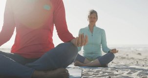 Animation of text good vibes only, in shiny pink, with happy senior women meditating on beach. positive feelings and wellbeing concept, digitally generated video.