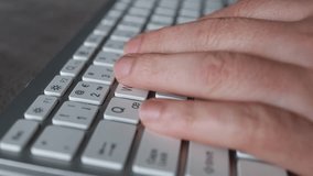 Close-up of male hands typing on laptop keyboard indoors. Businessman working in office or student browsing information. High quality video
