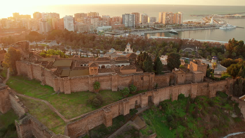 Aerial view of medieval Moorish castle of Alcazaba at sunrise in Malaga, Andalusia region, Spain. Drone orbit shot. Historic fortress on the hill with Malaga cityscape in beautiful morning light Royalty-Free Stock Footage #1101785901