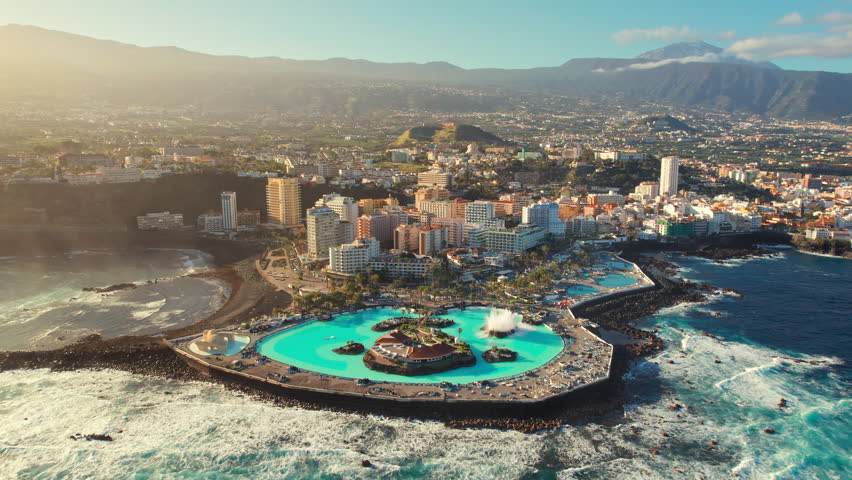 Aerial view of Puerto de la Cruz cityscape with, Tenerife, Spain. Purto de la Cruz town with Teide volcano at background during sunrise on Tenerife, Canary islands. Orbit shot