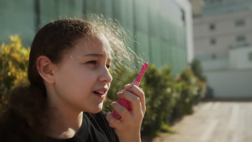 Child is playing cheerfully on a park. Happy kid concept. Child playing in the park at sunset girl child talking on walkie-talkies with other children. Happy kids in the concept of playing in the park | Shutterstock HD Video #1101790843