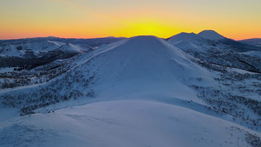 Colourful sunrise over a snowy landscape of extinct volcanoes. | Shutterstock HD Video #1101796385