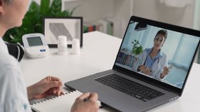 Mature Asian woman have video call with doctor at home. Female patient talk consult with physician online on webcam conference on computer.