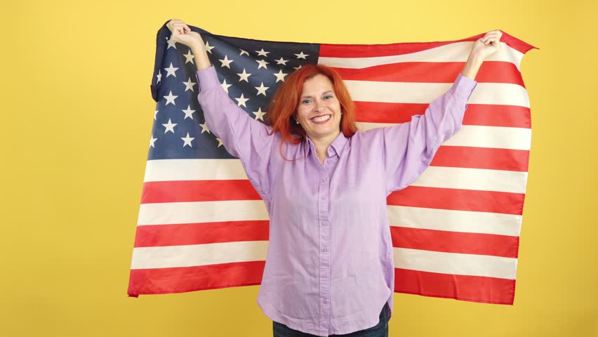 Happy mature woman wrapping with a USA national flag