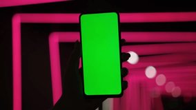 Woman using Chroma Key Smartphone while Standing, Gesturing, Swiping, Scrolling. Night City Street Full of Neon Light. Female Using Green Screen Mobile Phone. Over the Shoulder Close-up Shot