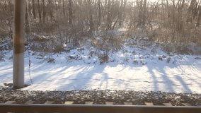 4k video, View of the railway track from the window of a fast train. A quick glimpse of a winter landscape with trees and snow