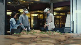 Male architect uses VR headset and wireless controllers, presents modern hi-tech building and park architectural project in virtual reality to colleagues. 3D hologram. Future digital AI technologies. - Powered by Shutterstock - Get 15% off with code: PIKWIZARD15