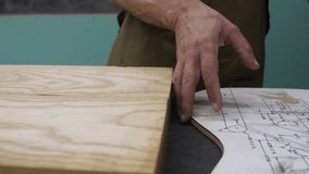 30 seconds video in Full Hd with slider movement of the hands of a luthier building a handmade electric guitar at the moment of drawing the shape of the guitar body with the template.