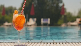 Cold and refreshing aperol spritz cocktail is the perfect summer drink at poolside. Slow motion 4k video.