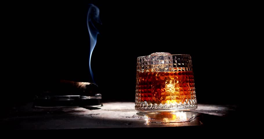 Glass of whiskey and smoking cigar on table. Slow motion, copy space, black background. Whiskey, brandy, cognac, alcoholic drink . Royalty-Free Stock Footage #1101817709