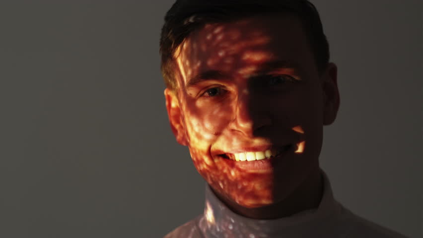 Masculine energy. Happy man. Double exposure portrait. Excited guy in white sweater posing gray with shimmering sparkles sand flow overlay background motion view.